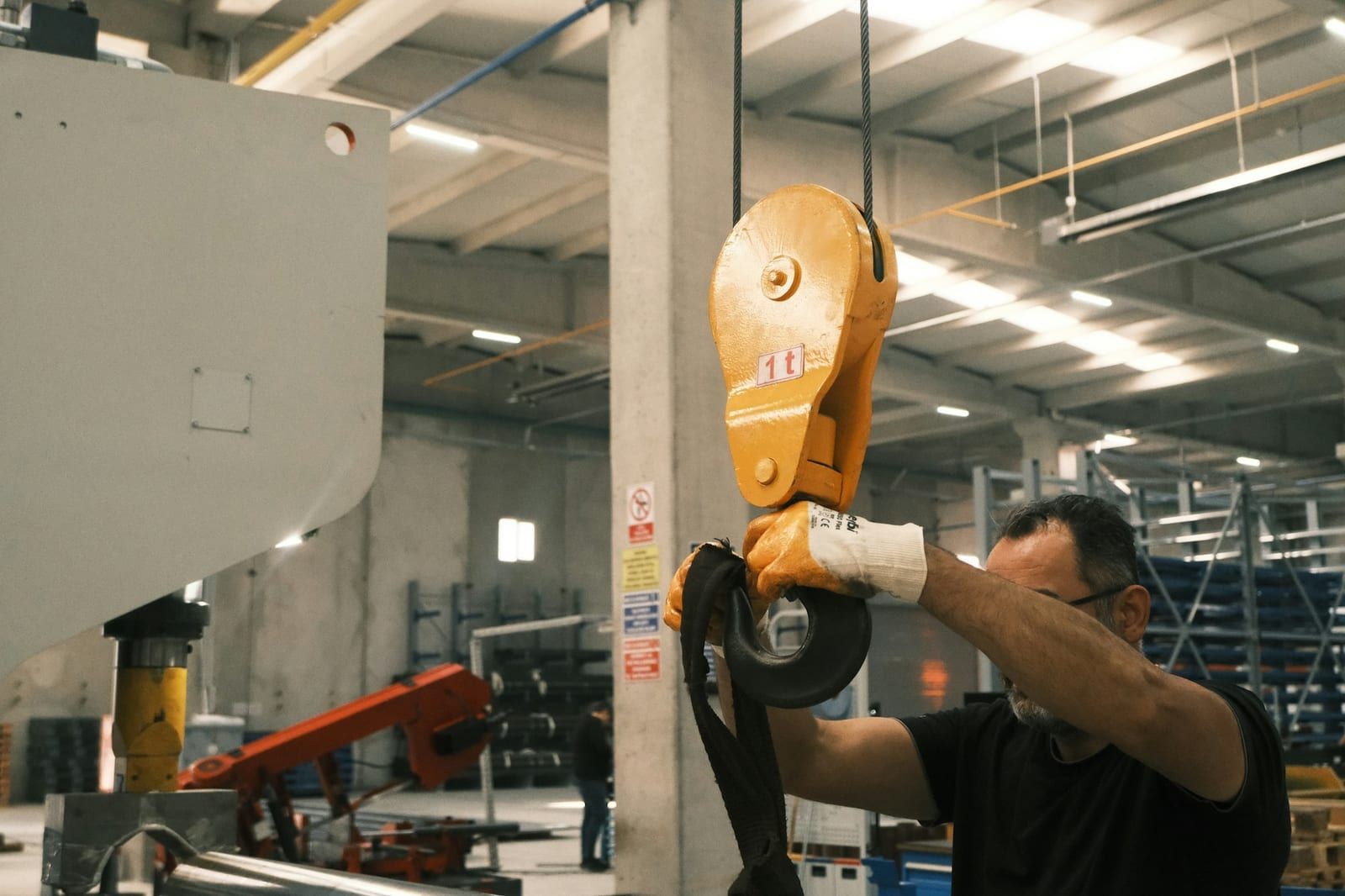 Worker guiding a yellow crane hook block by hand